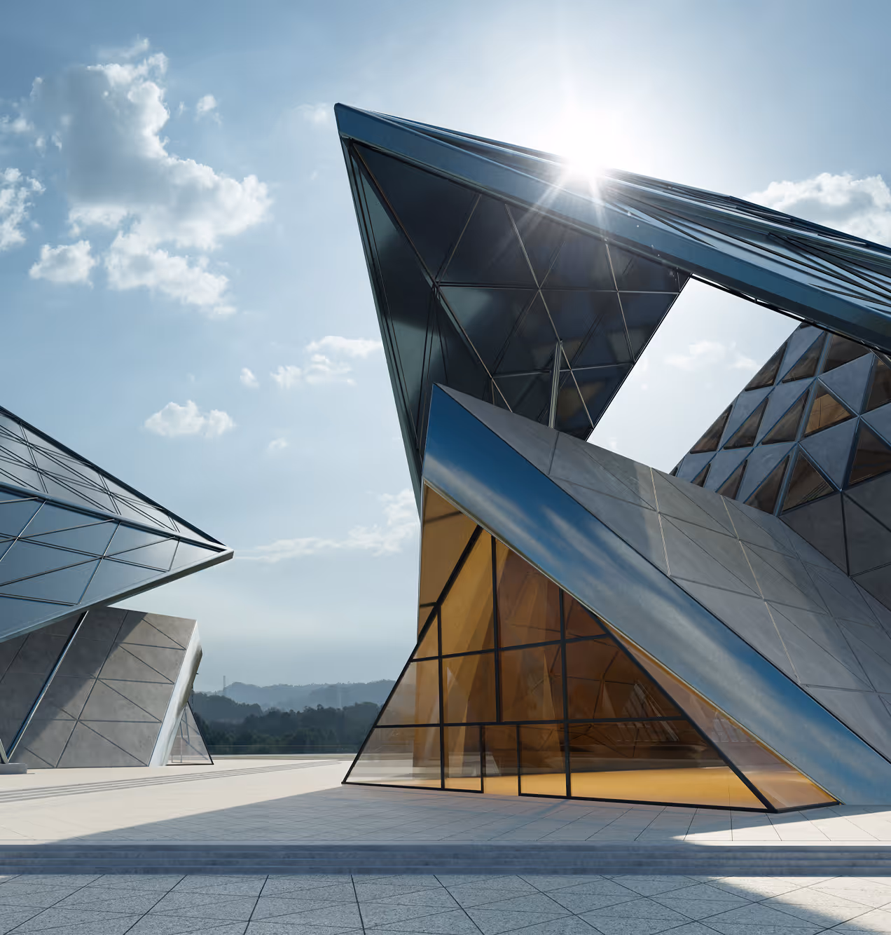 Futuristic modern building with angular glass and metal architecture under a bright sky with the sun shining.