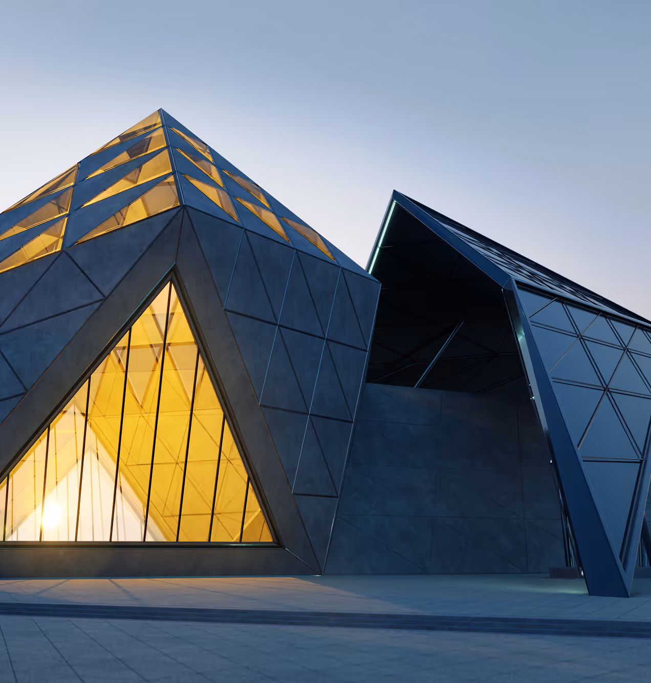 Modern angular building with geometric triangular windows illuminated with warm yellow light at dusk.